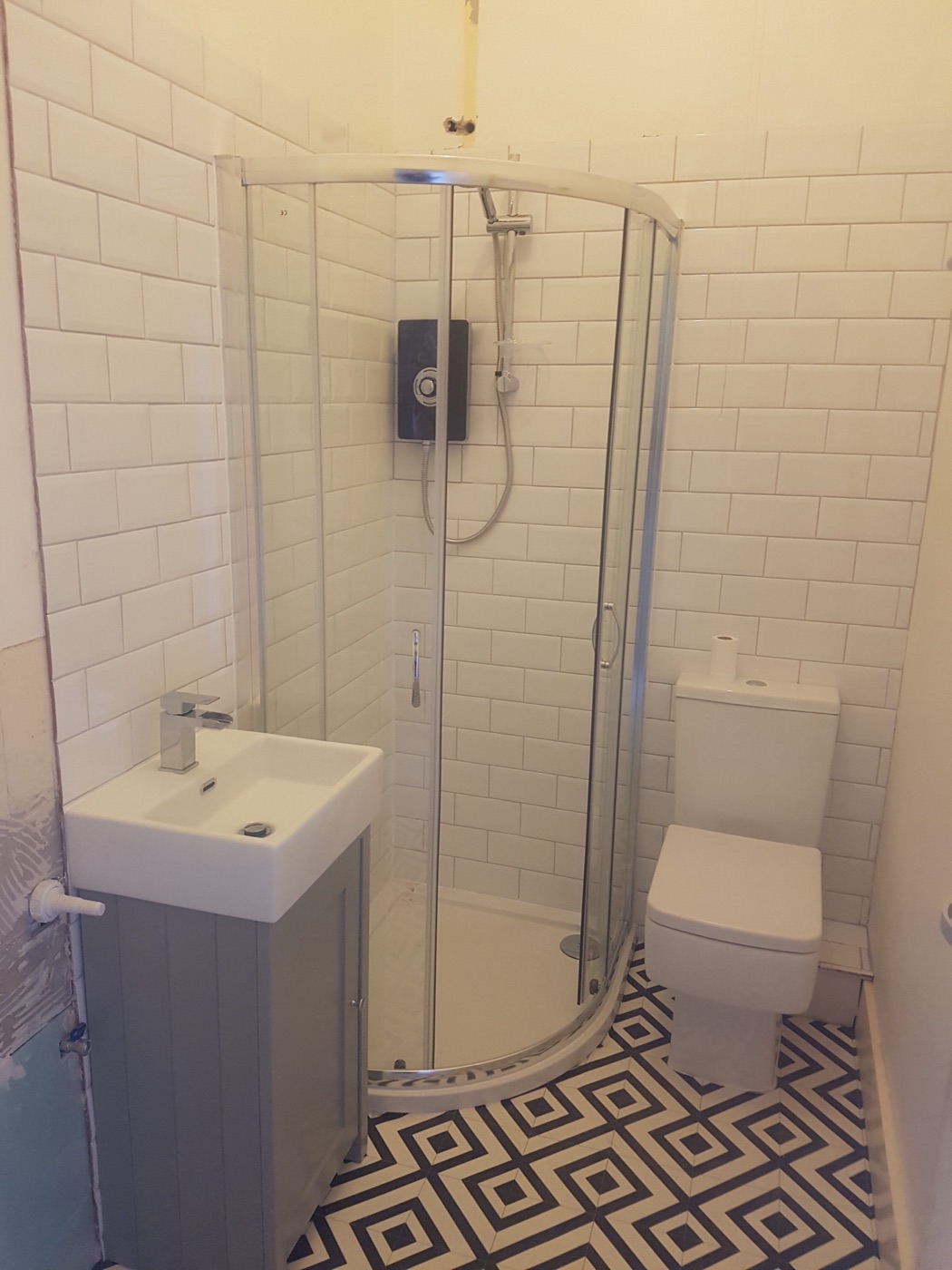 Quadrant shower, grey vanity unit and geometric patterned floor