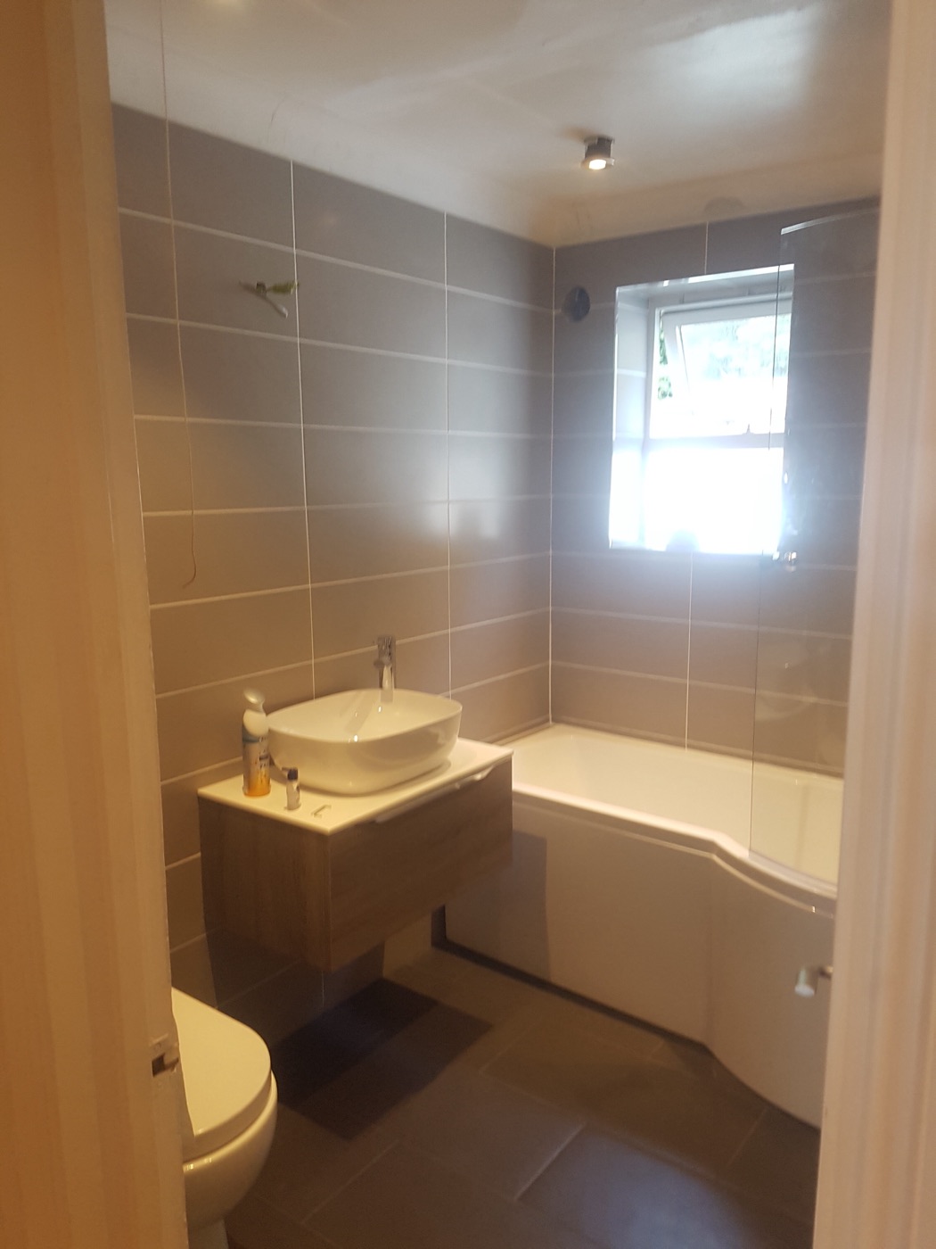 Floating vanity with vessel basin and P-shaped shower bath