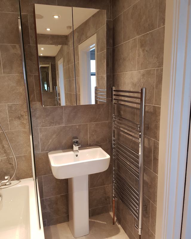 Stone tiled en-suite with a heated towel rail